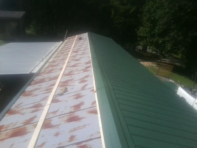 Old rusted panels beside newly installed green metal roofing — Wind Damage Roof Repair by Roofing Brothers in Presto