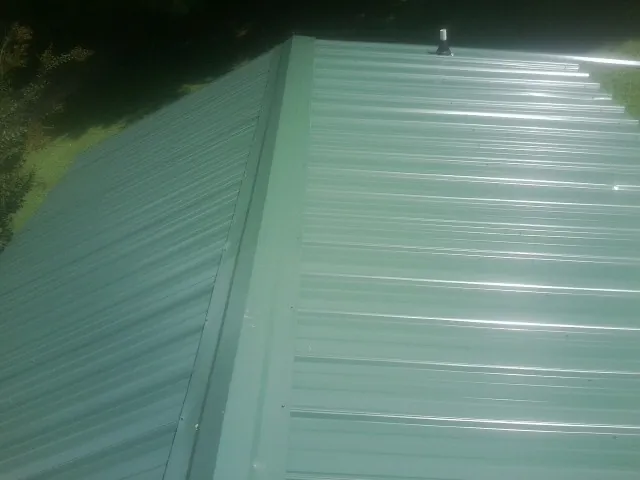 New green metal panels meeting at the ridge of a roof — Flat Roof Repair work by our crew in Presto