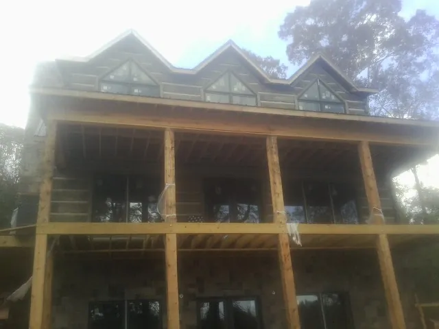 Dormers and porch framing on a large log home under construction — Roof Coating work by our crew in Presto