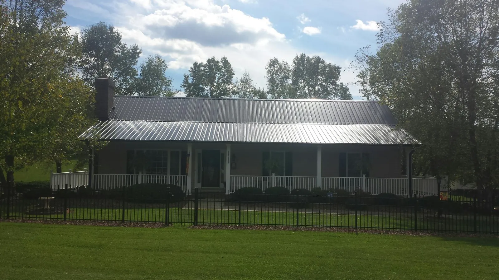 Gray metal roof on a brick ranch with a full width front porch — Gutter Guard Installation work by our crew in Presto