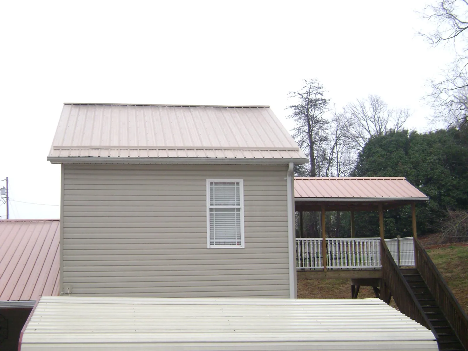 Tan metal roofs on a two story addition and attached porch, from a Roof Replacement job in Presto